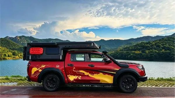 Red ute with a slide-on camper by a mountain lake