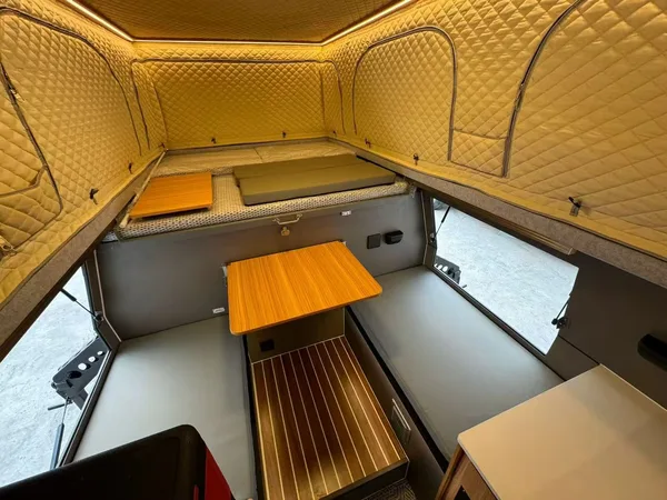 Slide-in camper interior with bench seats and wood table
