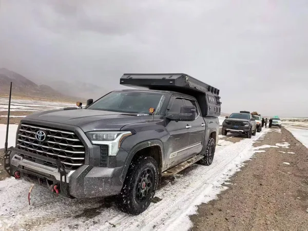 Toyota Tundra with a slide-on camper on a snowy plateau road