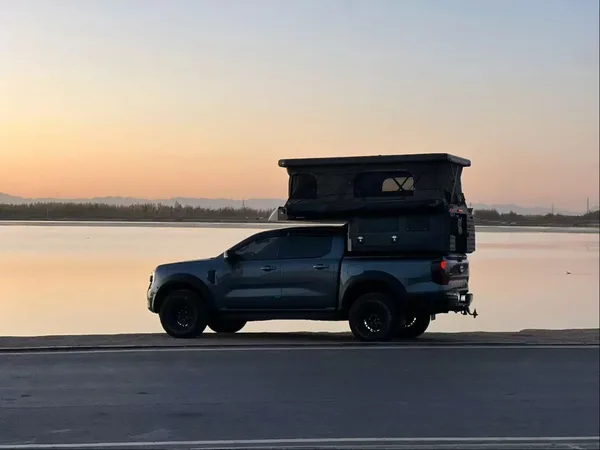 Slide-in camper on a ute at sunset by the water