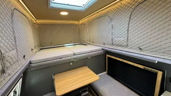 Slide-in camper interior with table and roof hatch