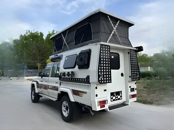 White Toyota Land Cruiser 79 with a SUNHOMEE tray-mount camper, pop-up roof raised, rear view