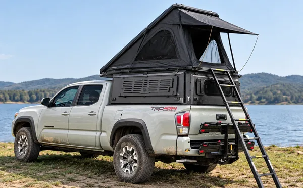 Integrated pop-up canopy with the hard-shell tent open on a white Toyota Tacoma by a lake