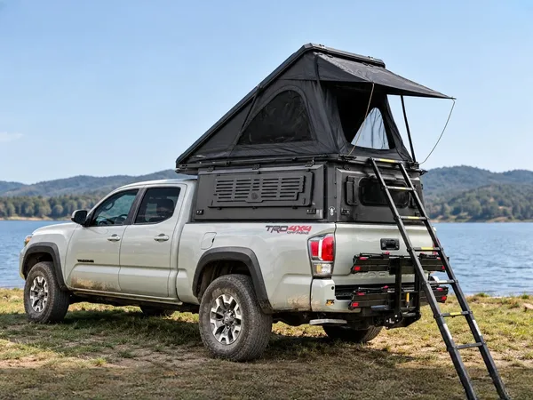 Integrated pop-up canopy with the hard-shell tent open on a white Toyota Tacoma by a lake