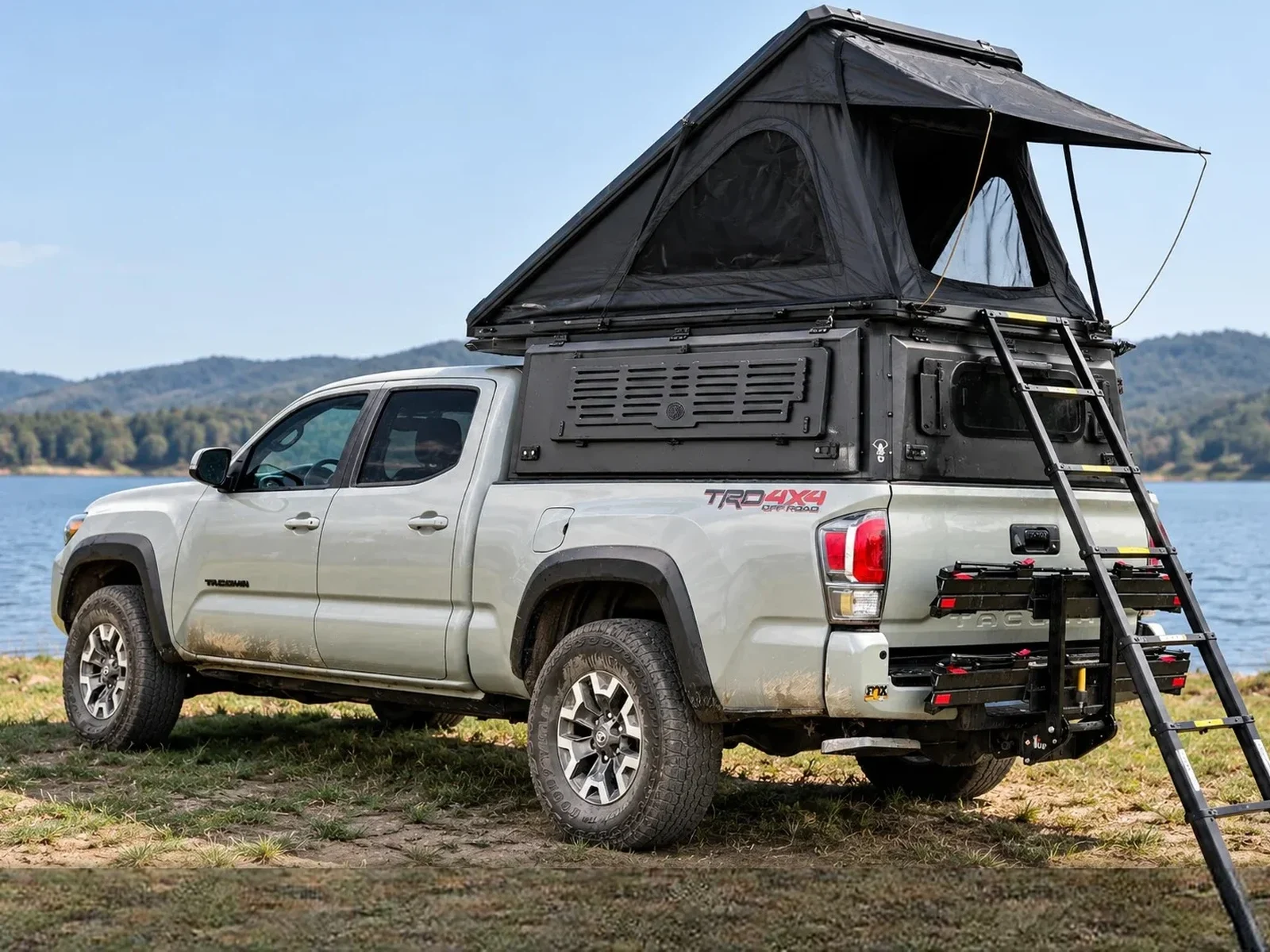 Integrated pop-up canopy open on a white Toyota Tacoma by a lake