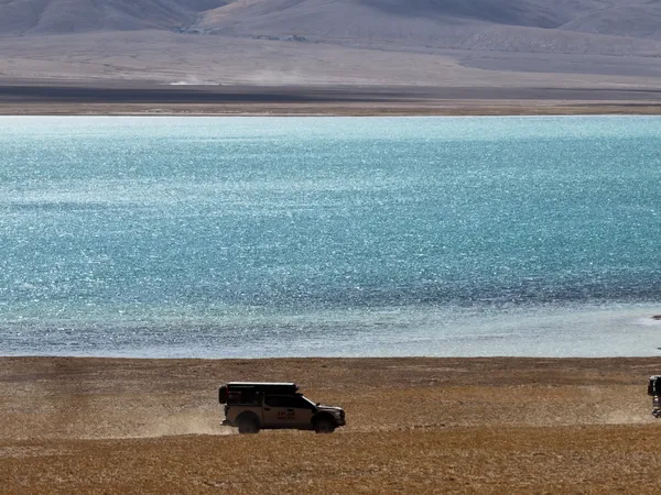 Camper utes driving along a turquoise high-altitude lake
