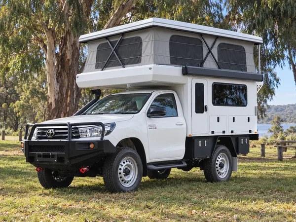 Front three-quarter view of a Toyota Hilux with a white SUNHOMEE tray-mount camper