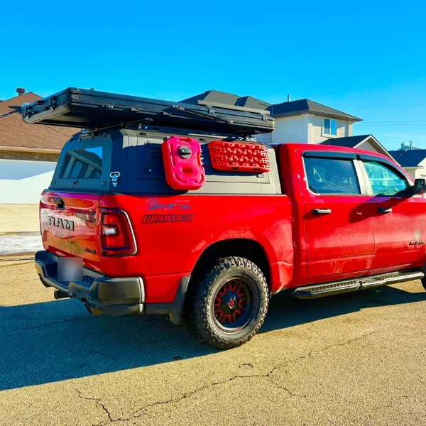 Red RAM 1500 with a SUNHOMEE aluminum truck topper, roof rack and recovery boards