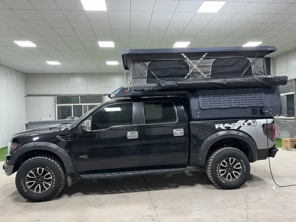 Ford Raptor with a SUNHOMEE slide-in camper, roof raised and awning
